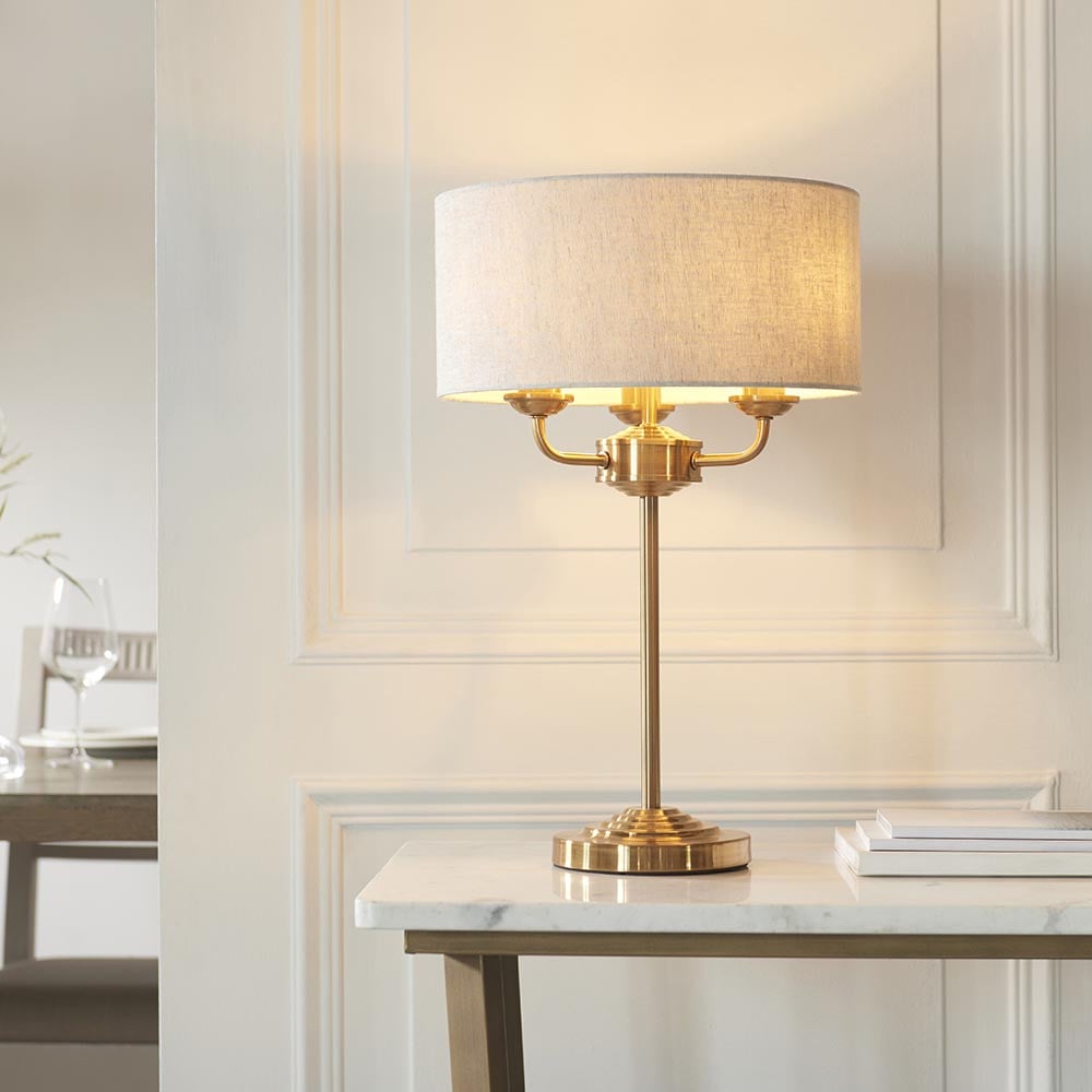 Product photograph of Hixson 3 Light Natural Fabric Table Lamp In Vintage Brass from Furniture in Fashion