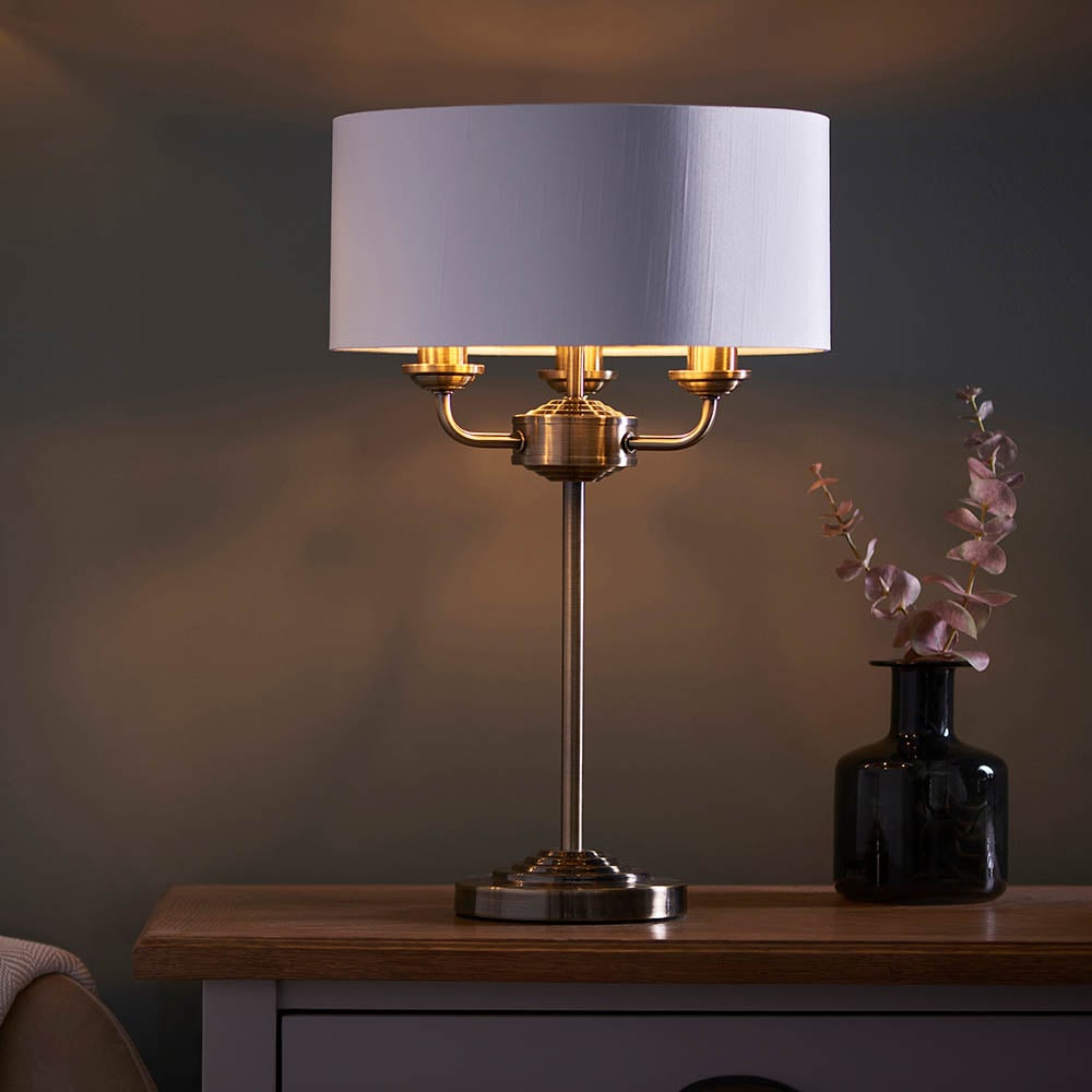 Read more about Hixson 3 light white fabric table lamp in antique brass